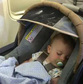 A baby in a car seat on a plane
